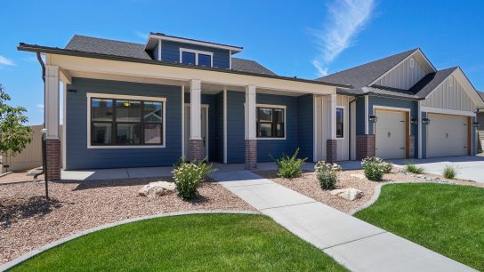 modern landscaped new construction home with blue sky and puffy white clouds. Covered front porch with three car garage